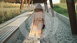 Rear view of brunette in coat walking, turning around and looking at camera