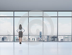 Rear view of brunette woman in the office who looks through the window.