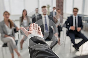 Rear view.Business coach gesturing his hand in front of a group of people.