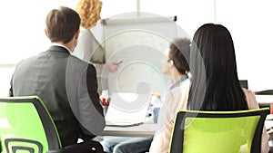 Rear view of business team at the meeting, woman spinning on chair with board in her hands.