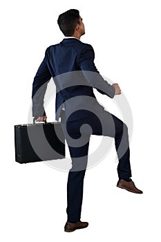 Rear view of businessman with briefcase climbing invisible steps