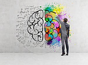 Rear view of businessman drawing colorful brain icon on concrete