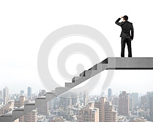 Rear view businessman gazing at city on concrete stairs top
