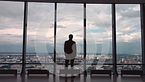 Rear view of businessman in an office with panoramic city view. Businessman admires the city from the panoramic Windows