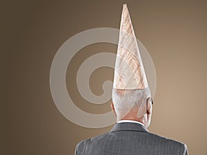 Rear View Of Businessman Wearing Dunce Hat