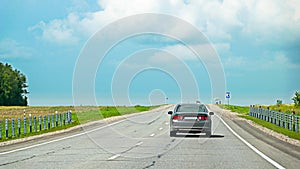 Rear view of a car speeding on asphalt road in countryside