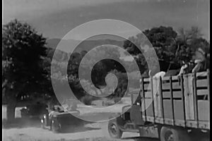 Rear view of a caravan of cars and trucks driving on a dirt road