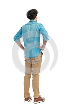 rear view of casual curly hair man holding hands on hips and standing