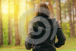 Rear view of casual female looking at sunlight through trees