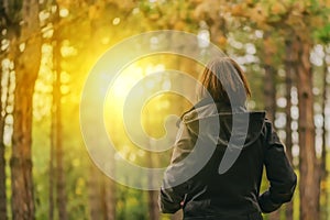 Rear view of casual female looking at sunlight through trees