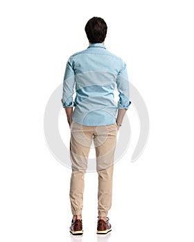 rear view of casual man in denim shirt with chino pants holding hands in pockets