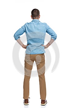 Rear view of casual man with hands on hips standing