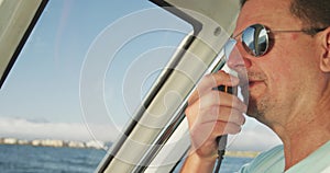 Rear view of a Caucasian man on boat using a walkie-talkie