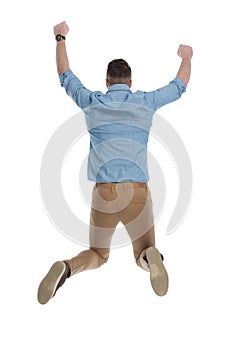 Rear view of celebrating casual man jumping