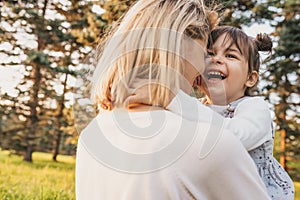 Rear view of cheerful happy girl kid playing with her mother outdoor. Portrait of woman and her cute child laughing in the park