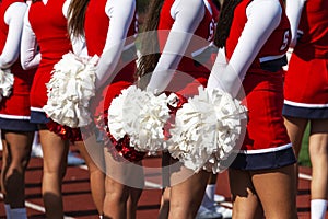 Rear view of cheerleaders with their red and white pom poms behind them