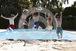 Rear View Of Children Jumping Into Outdoor Swimming Pool