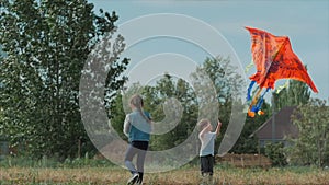 Rear view children play with a kite, a little girl and a boy let a flying snake in the meadow. Happy and carefree