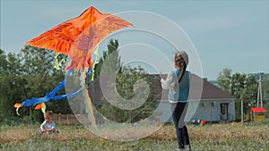 Rear view children play with a kite, a little girl and a boy let a flying snake in the meadow. Happy and carefree