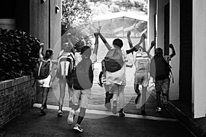 Rear view of classmates running at school campus