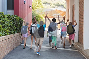 Rear view of classmates running at school campus