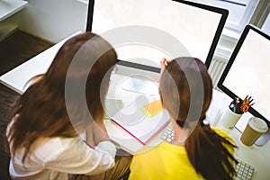 Rear view of colleagues working on computer screen at creative office