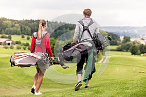 Rear view of couple carrying golf bag