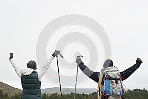 Rear view of couple raising hands after a trek