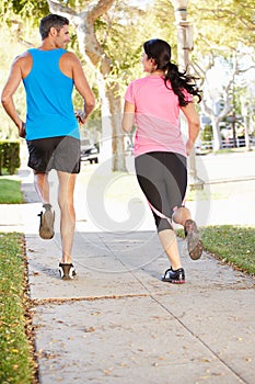 Rear View Of Couple Running On Suburban Street