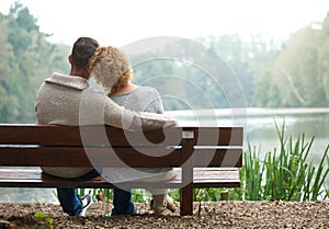 Rear view couple sitting on bench outdoors