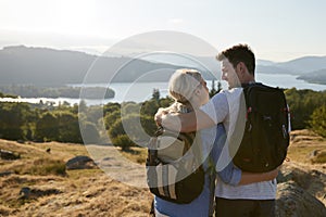 Rear View Of Couple Standing At Top Of Hill On Hike Through Countryside In Lake District UK