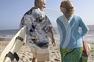 Rear View Of A Couple With Surf Boards On Beach