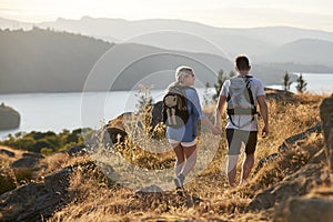 Rear View Of Couple Walking On Top Of Hill On Hike Through Countryside In Lake District UK