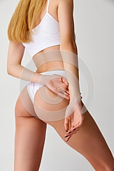 rear view of cropped beautiful sensual slender female body, buttocks wearing white inner wear posing over studio