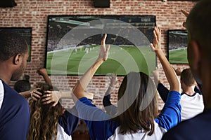 Rear View Of Disappointed Friends Watching Game In Sport Bar