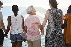 Rear view of diverse senior women holding hands together at the