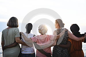Rear view of diverse senior women standing together at the beach photo