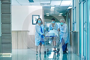 Rear view of doctors running for the surgery.  Hospital Emergency team carrying stretcher with patient through hospital hall