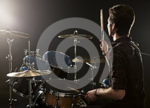 Rear View Of Drummer Playing Drum Kit In Studio