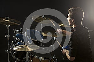 Rear View Of Drummer Playing Drum Kit In Studio