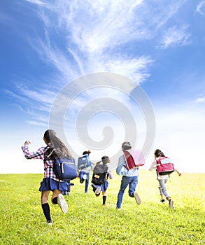 Rear view of elementary school kids running on the grass