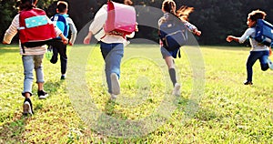 Rear view of elementary school kids running on the grass