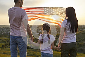 Rear view Family with American moisture in nature at sunset. US Independence Day Celebration July 4th