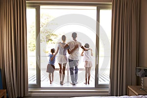 Rear View Of Family On Balcony Looking Out On New Day