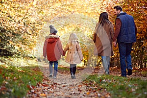 Rear View Of Family With Parents And Children Holding Hands Walking On Path In Autumn Countryside