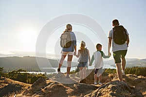 Rear View Of Family Standing At Top Of Hill On Hike Through Countryside In Lake District UK