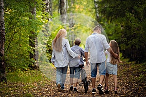 Rear view - a family with two children walks in park