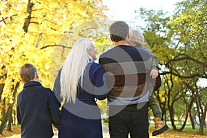 A rear view of family with two small children on a walk in autumn nature.