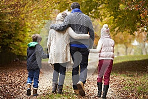 Rear View Of Family Walking Along Autumn Path