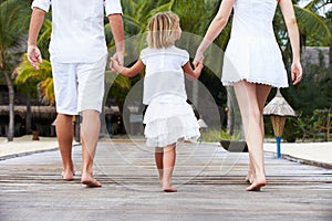 Rear View Of Family Walking On Wooden Jetty